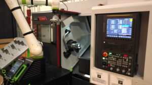 Automated lathe operating on a modern manufacturing floor with skilled operators overseeing production.