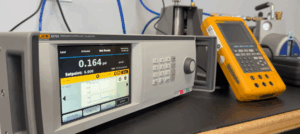 Close-up of a pressure calibration setup with a Fluke 6270A controller and handheld calibrator on a lab bench.